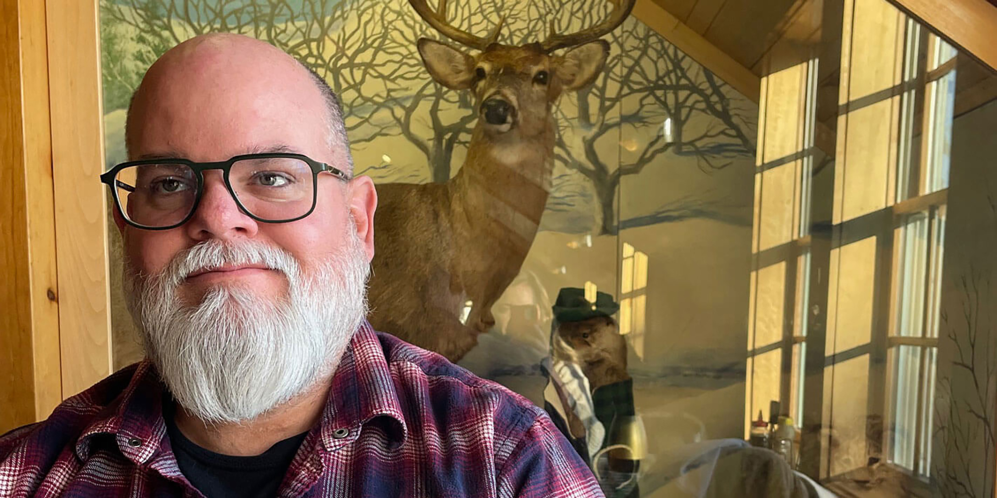 Milwaukee Film Membership Director Kristopher Pollard standing in front of a display case featuring a taxidermied deer
