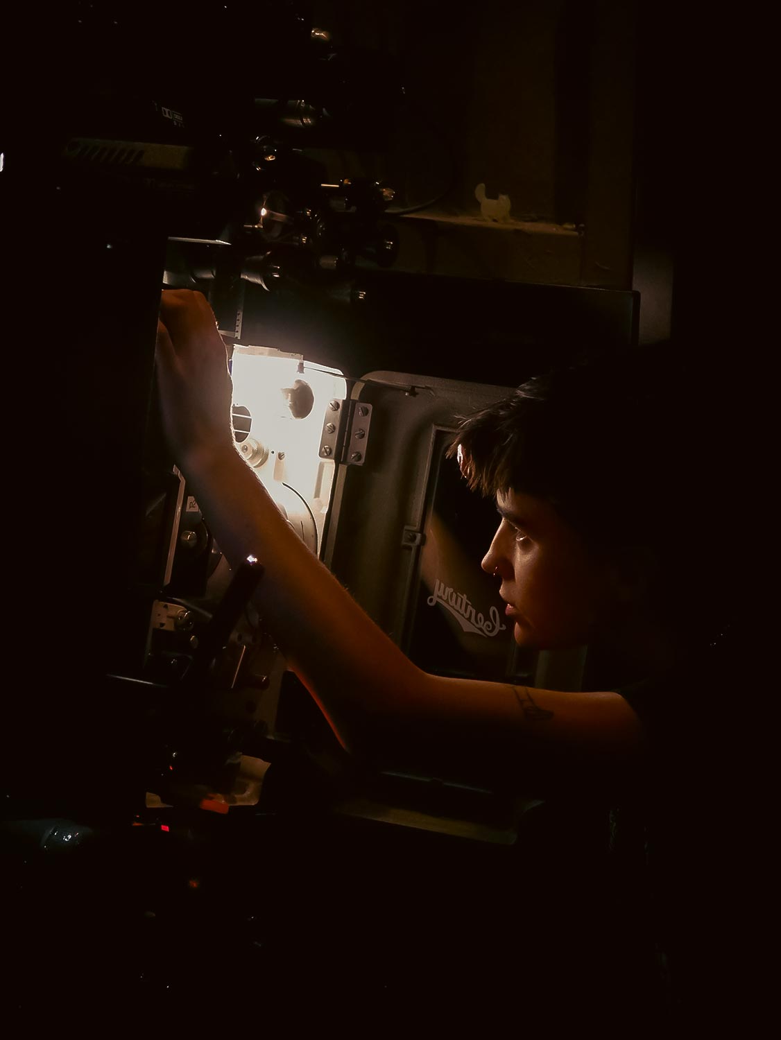 Projectionist with a headlamp inspects the inside of a century JJ Projector Photo by Jolee Mallmann