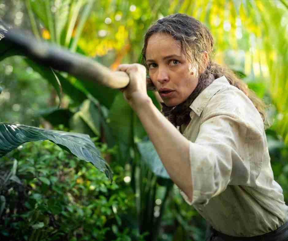 Send Help film still Rachel McAdams holds a long wooden spear against a forest backdrop