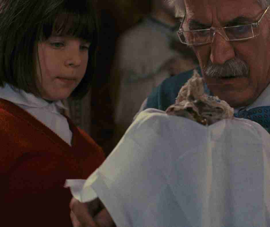 Cronos film still a small girl and a man look at an item in the man's hand carefully placed on a small towel.