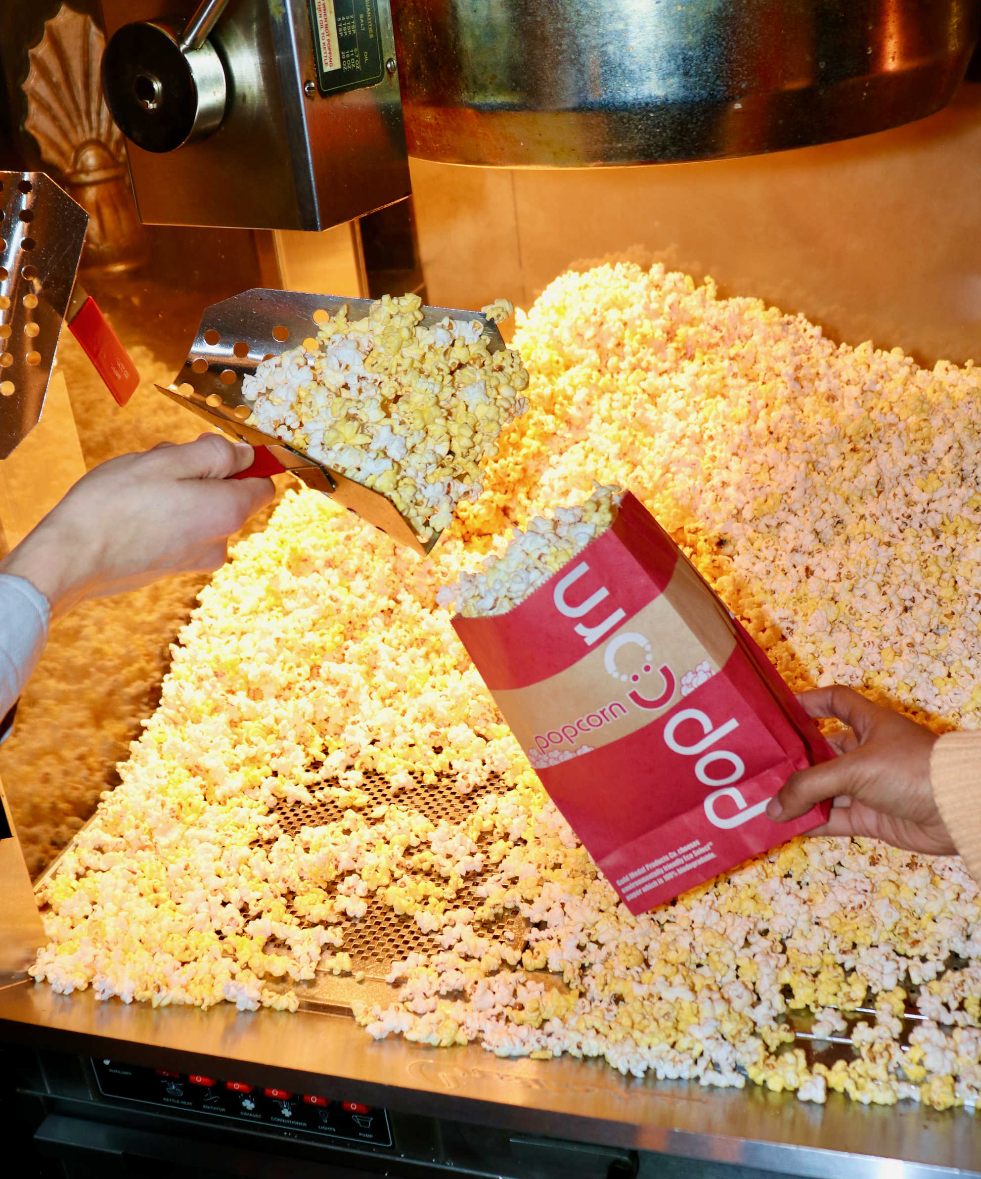 Scooping Popcorn in front of popcorn machine