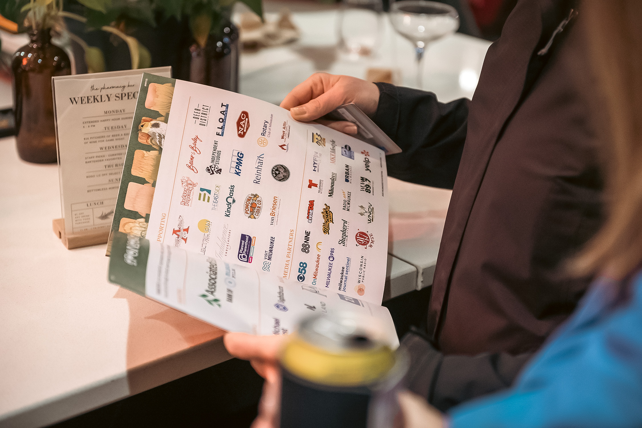 Hands hold a program book opened up to festival sponsors page filled with logos from festival sponsors and community partners.