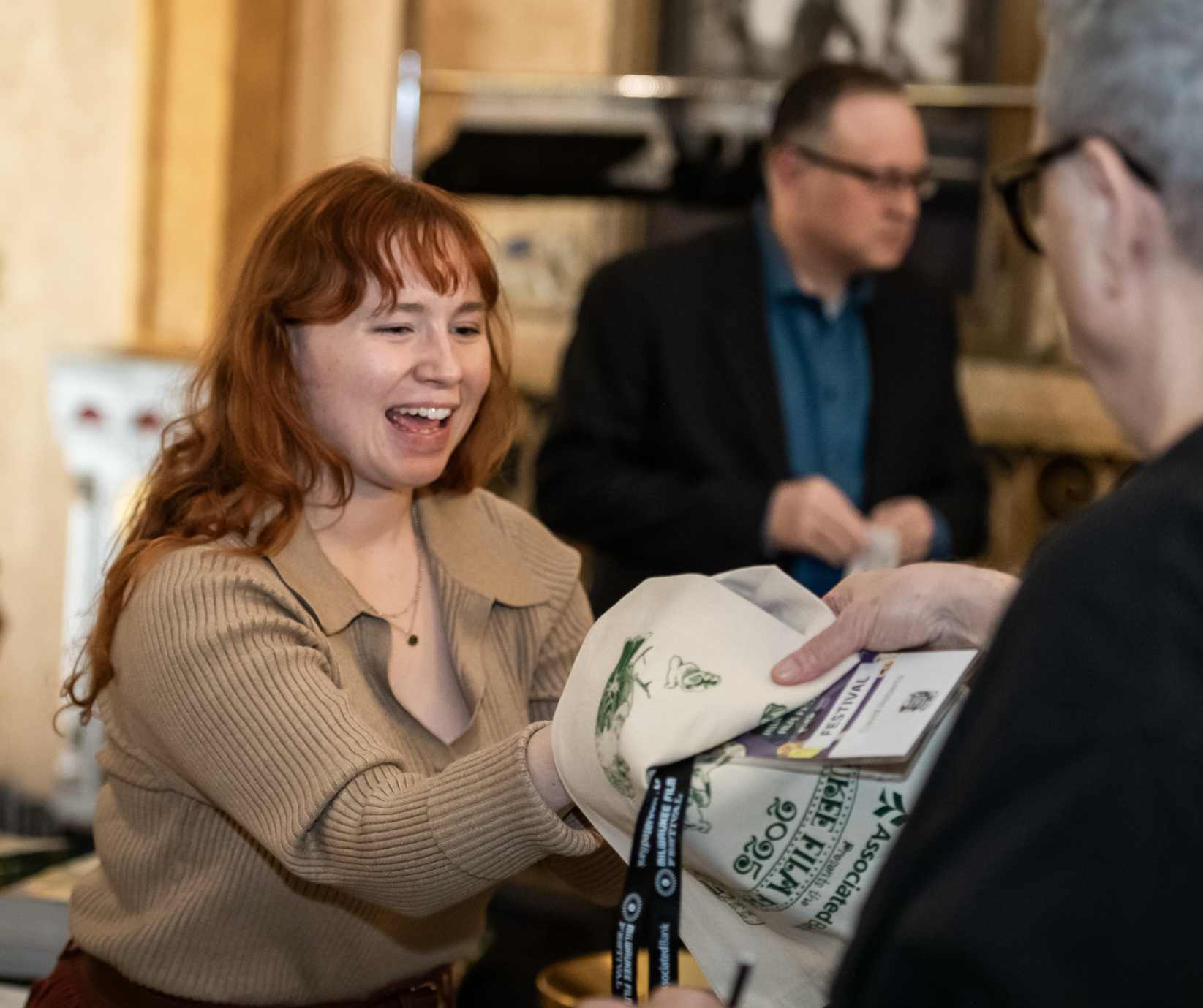 Staff member handing out a festival tote to a partron. Photo by Valerie Hill