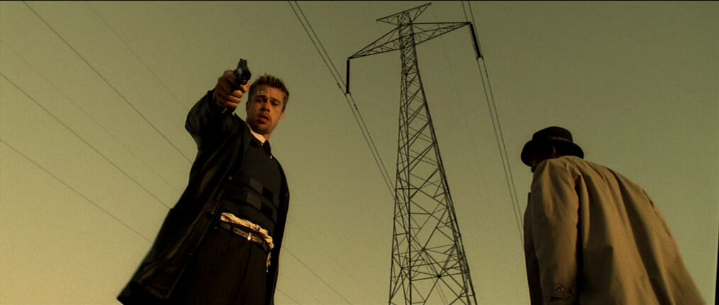 Se7en Film Still A man on the left points a gun downwards and another man faces away.