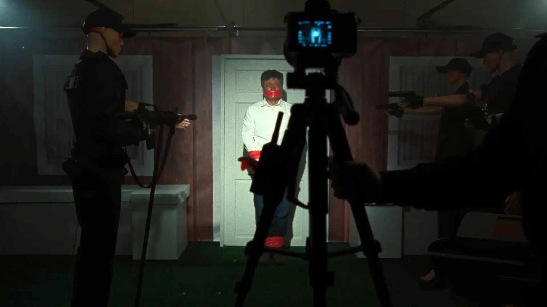 Faces Of Death Film Still A man with his mouth and hands taped stands in front of a white door with a camera facing him