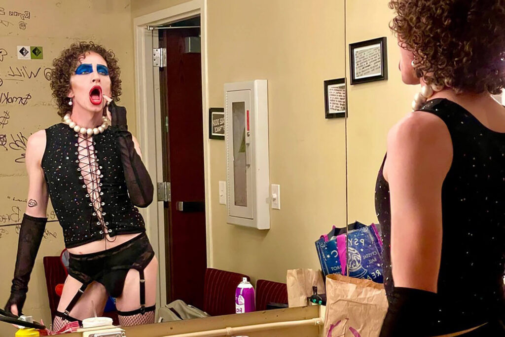Still from the documentary Time Warp, featuring a human actor putting on their makeup in the style of the main character of Rocky Horror Picture Show