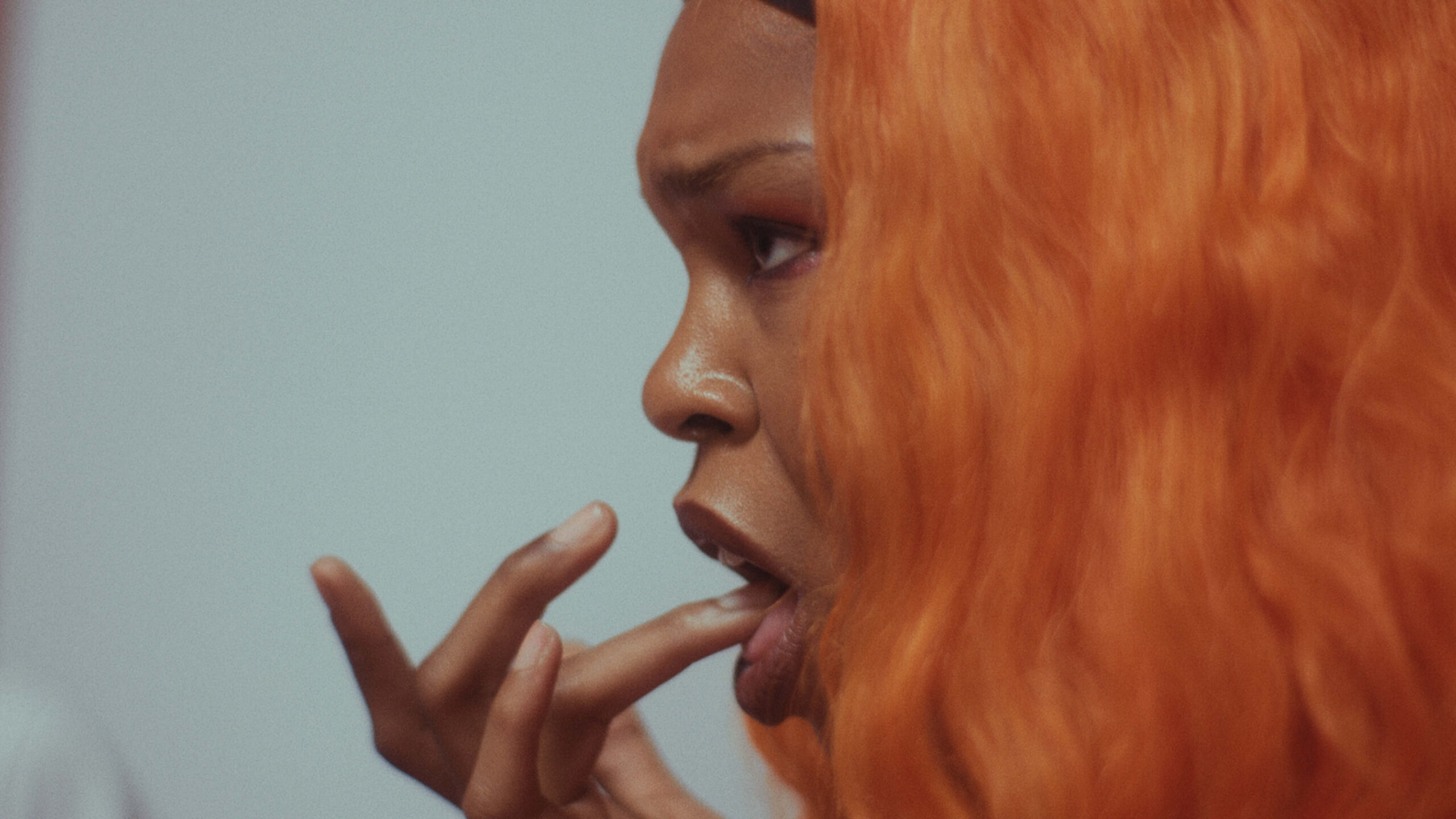 The African Desperate Film Still A Woman with bright orange hair bites her finger tip