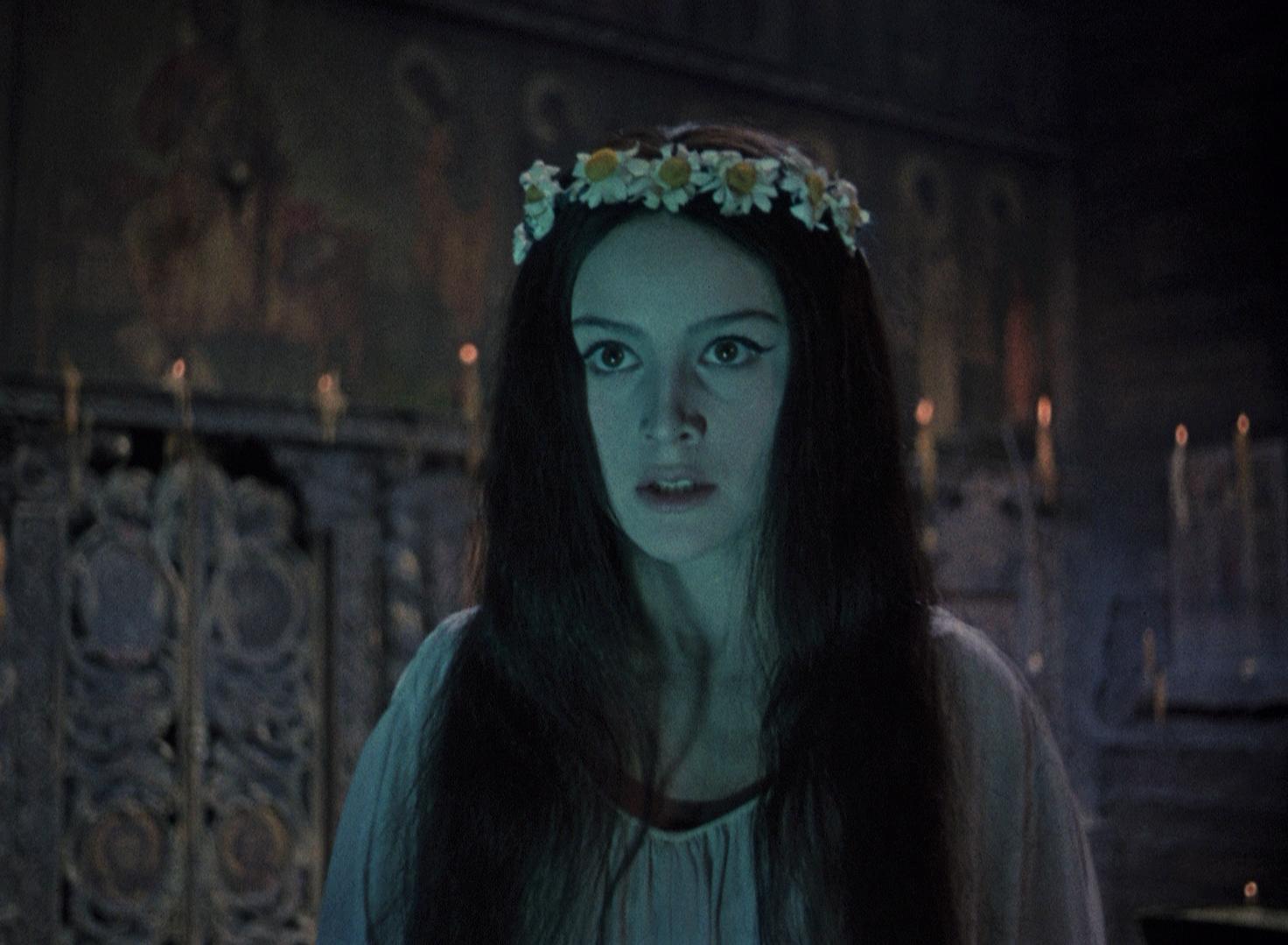 VIY Film Still A young woman looks forward with a white flower crown and long straight brown hair.
