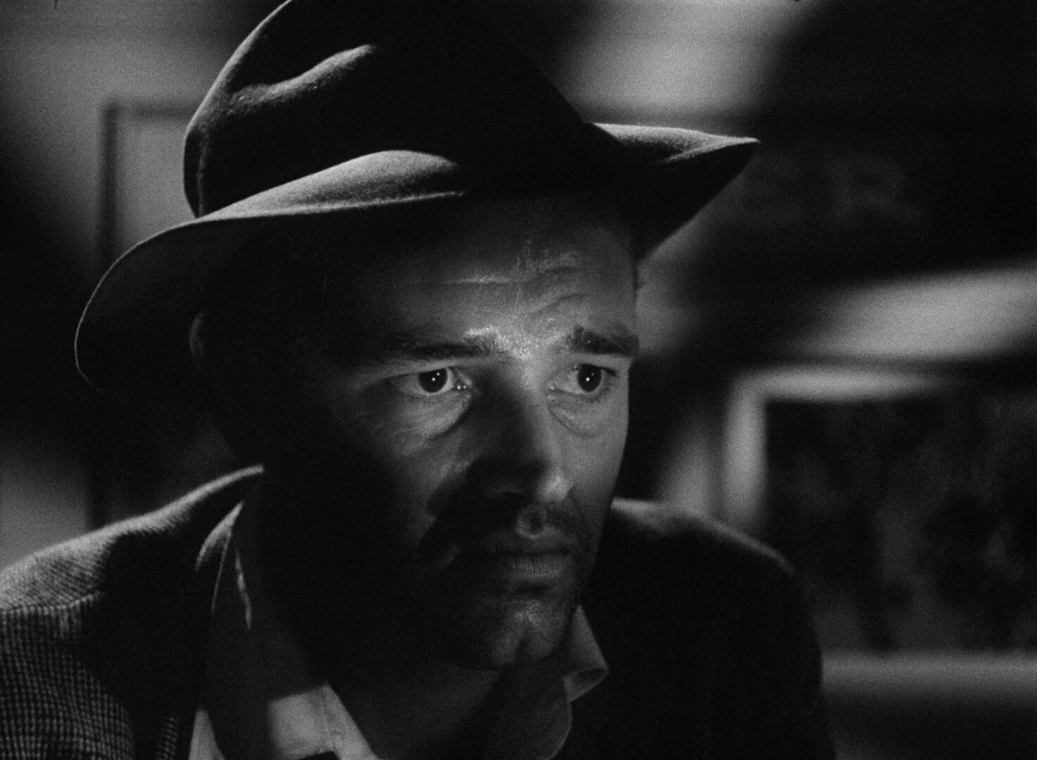 Detour Film Still Black and White close up image of a man's face with a small patch of light over his eyes.